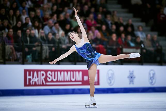 A person ice skating on ice with a crowd watchingAI-generated content may be incorrect.
